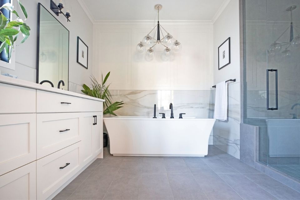 Large soaking tub in tiled bathroom with gray tile